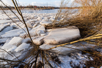 Close up view of ice drift on the frozen river. Melting ice. Pieces of ice have formed near the...