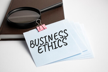Magnifying Glass with Business Ethics sign on the paper sheet