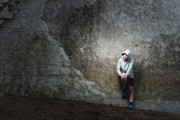 Serious thoughtful hispanic sportsman resting against a natural wall
