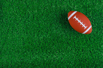 Green grass sports field with american football ball.