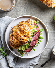 Fresh croissant sandwich with ham and salad leaf with coffee on textured background, top view