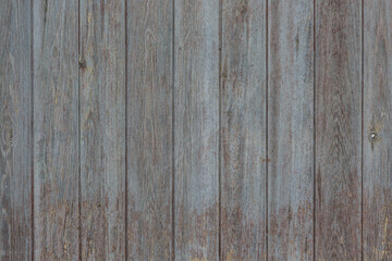 An old fence made of vertically assembled boards. Background, texture.
