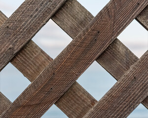A fragment of a decorative fence lattice of boards. An old trellis fence.