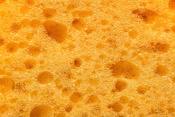 Foam sponge texture in macro. Textured background. Dishwashing or car cleaning concept. Abstract yellow wallpaper or backdrop for your design closeup 