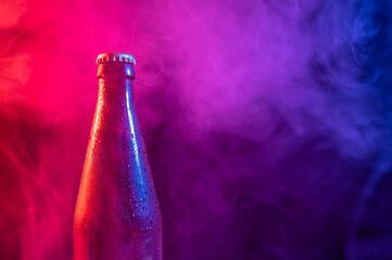Glass bottle of beer in blue pink mist