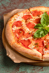 Pepperoni pizza on a concrete background with basil