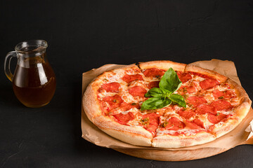 Pepperoni pizza on a concrete black background with basil