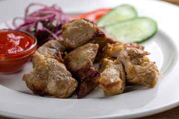 skewers of mutton flesh on white plate  with vegetables and tomato sauce macro close up