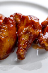 chicken wings in teriyaki sauce on white plate macro close up