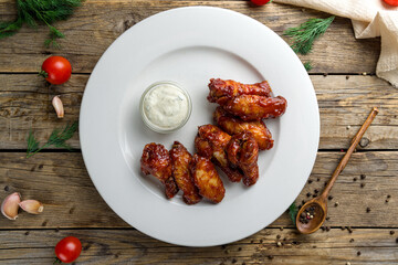 chicken wings in barbecue sauce on white plate on wooden table