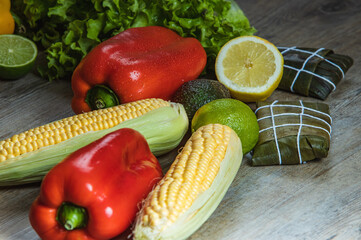 I LOVE FOOD SERIES. Latin American food on a wooden table with fresh, healthy and natural ingredients, such as corn, red pepper, hallacas, humita, tamale, carrot, tomato, lime, perfect for a dinner.