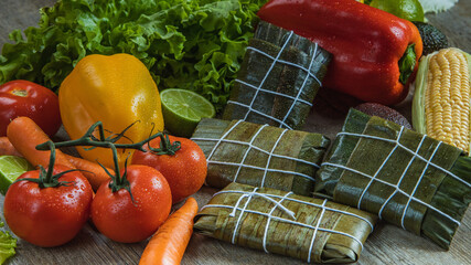 I LOVE FOOD SERIES. Latin American food on a wooden table with fresh, healthy and natural ingredients, such as corn, red pepper, hallacas, humita, tamale, carrot, tomato, lime, perfect for a dinner.