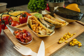 I LOVE FOOD SERIES. Latin American food on a wooden table with fresh, healthy and natural ingredients, such as corn, red pepper, hallacas, humita, tamale, carrot, tomato, lime, perfect for a dinner.