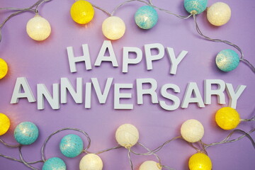 Happy Anniversary alphabet letters with LED Cotton ball Decoration on purple background