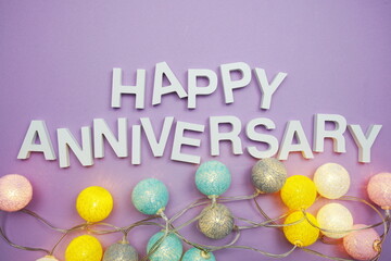 Happy Anniversary alphabet letters with LED Cotton ball Decoration on purple background