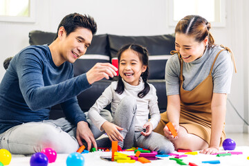 Portrait of enjoy happy love asian family father and mother with little asian girl smiling play with toy build wooden block board game in moments good time at home