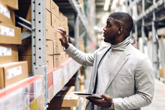 Portrait of smiling african american business man order details on tablet checking goods and supplies on shelves with goods background in warehouse.logistic and business export