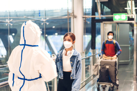 Doctor woman use infrared forehead thermometer for check body temperature scan travel passenger fever in quarantine for coronavirus omicron wearing safety mask at International terminal airport