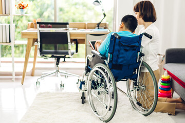 Portrait of enjoy happy love family asian mother playing and carer helping look at disabled son child sitting in wheelchair moments good time at home.disability care concept