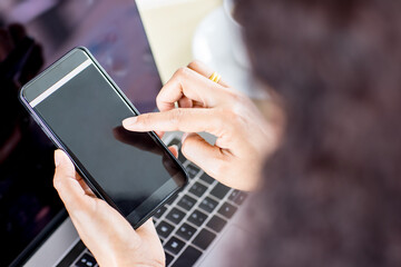 Businesspeople sitting in office over the working desk with computer and charts pater and coffee, hold smartphones with blank screens. Taken from top view angle