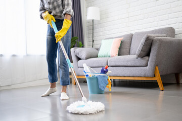 Cropped image of teenage girl holding a mop stick doing household chores is mopping the living room