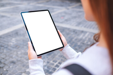 Mockup image of a woman holding digital tablet with blank white desktop screen in the outdoors