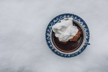 hot chocolate in blue and white Japanese teacup and saucer topped with meringue sitting outside in...