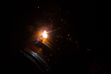 Close-up of a welder working in a workshop. Shallow depth of field. Welding of metal structures....