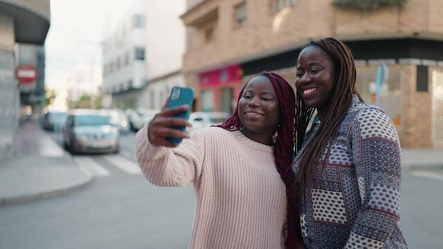 Two african american women smiling confident making selfie by the smartphone at street