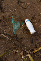 Poured trash on the beach of a big city. Empty used dirty plastic (glass) bottles. Dirty sandy river bank. Environmental pollution. Ecological problem.