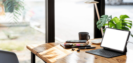 Mockup workspace with blank screen tablet and magic keyboard on wooden table, open workspace home office concept.