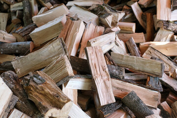 Small brown chopped firewood with grey bark pile lies