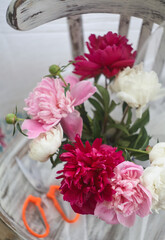Still life with white and pink peonies in a blue vase on vintaje chair