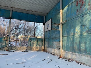 an abandoned soviet gym with a volleyball court, broken walls in the snow