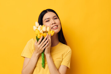 woman in a yellow t-shirt t-shirt with a bouquet of flowers holiday yellow background unaltered
