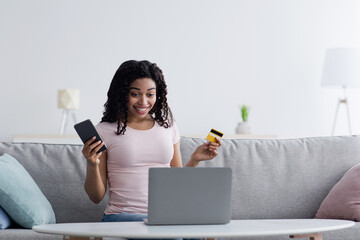 Young smiling woman using smartphone buying online shopping by credit card on sofa when relax in living room at home