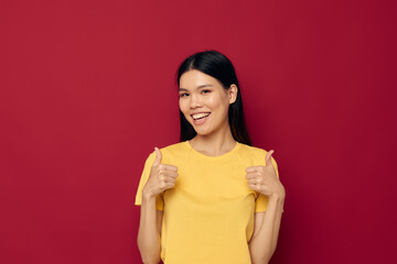 woman with Asian appearance gestures with his hands in a yellow t-shirt casual wear red background unaltered