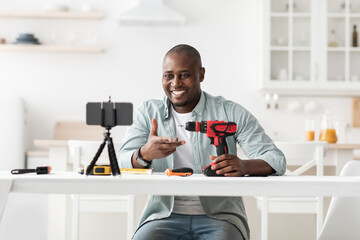 African american handyman recording video review of instruments, showing electric screwdriver and talking to smartphone