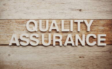 Quality assurance  alphabet letters on wooden background