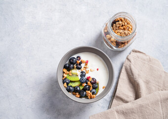 The concept of a healthy breakfast of vegetarian yogurt, granola and fresh fruit kiwi and blueberries on a blue background. Top view and copy .space