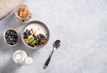 The concept of a healthy breakfast of vegetarian yogurt, granola and fresh fruit on a blue background. Top view and copy space