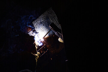 Welding metal with sparks. A man's hand in a glove with welding equipment welds metal structures.