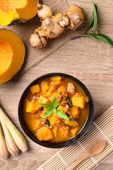 Thai spicy pumpkin curry soup with pork on wooden table, Top view