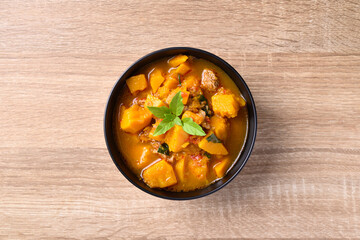 Thai spicy pumpkin curry soup with pork on wooden table, Top view