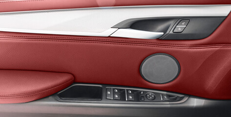 Obraz na płótnie Canvas Car door handle inside the luxury modern car with red leather. Switch button control. Modern car interior details. Red perforated leather