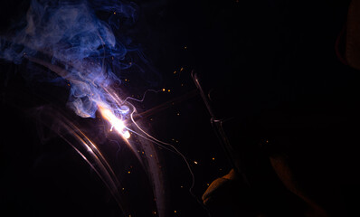 Close-up of a welder working in a workshop. Shallow depth of field. Welding of metal structures....