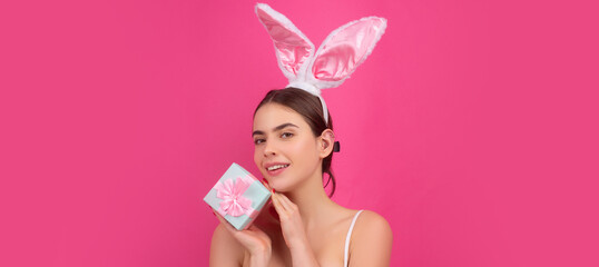 Obraz na płótnie Canvas Easter banner with bunny woman. Girl in bunny ears with gift present. Easter advertising. Rabbit woman with color box.