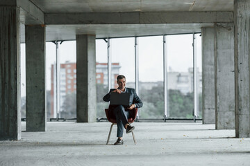 Businessman inside the building. Young man in formal wear is working indoors on the construction