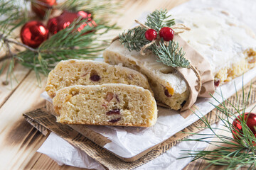 Christmass stollen cake with nuts, raisins and dried fruit on cutting board on wooden background, selective focus