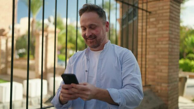 Young caucasian man smiling confident using smartphone at street
